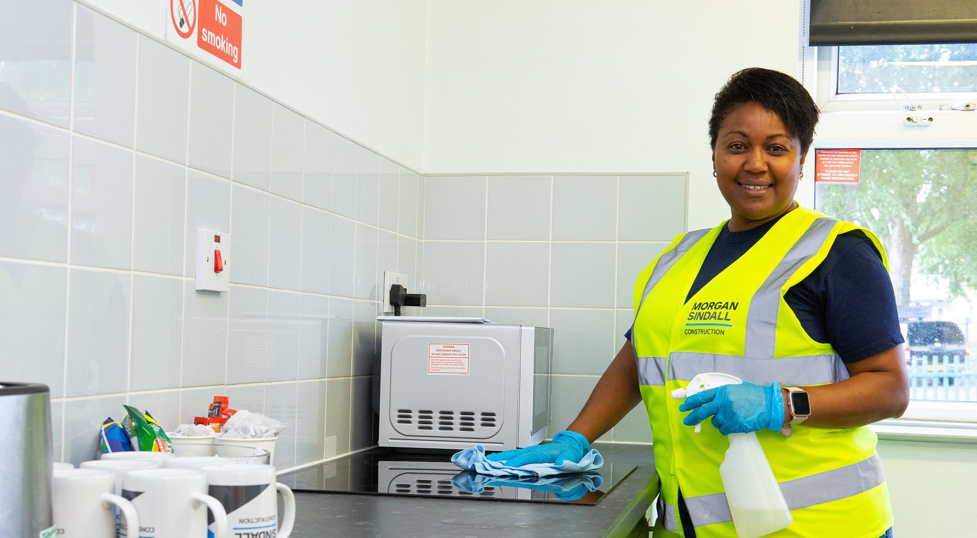 A woman cleaning a surface wearing a high vis jacket who is employed by Radiant Cleaners