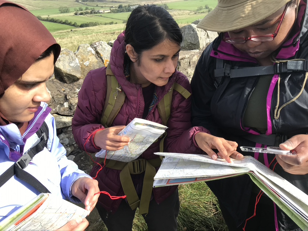 Three women checking their maps on a nature walk hosted by Earth Sea Love