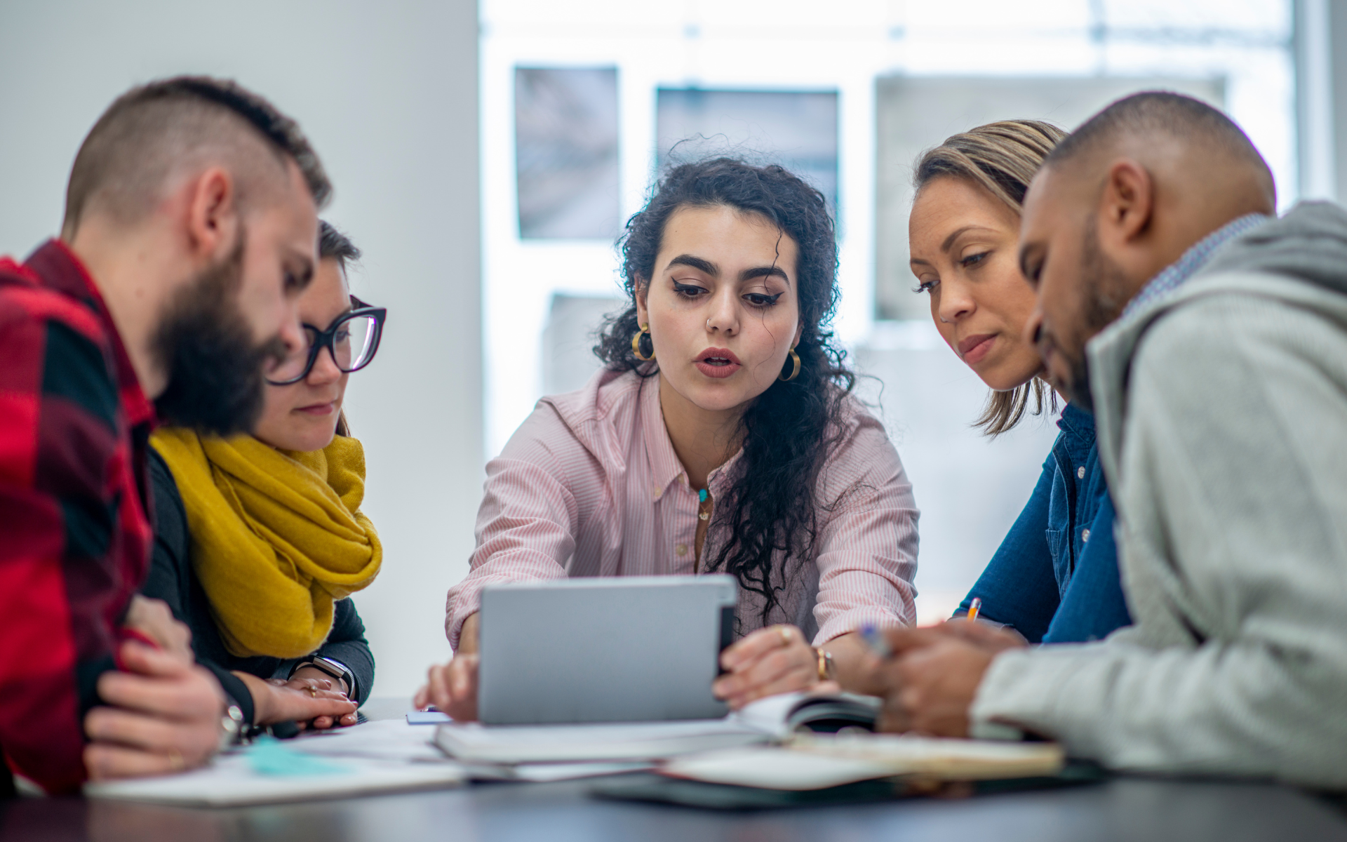 A group of people gathered around a laptop having a business discussion