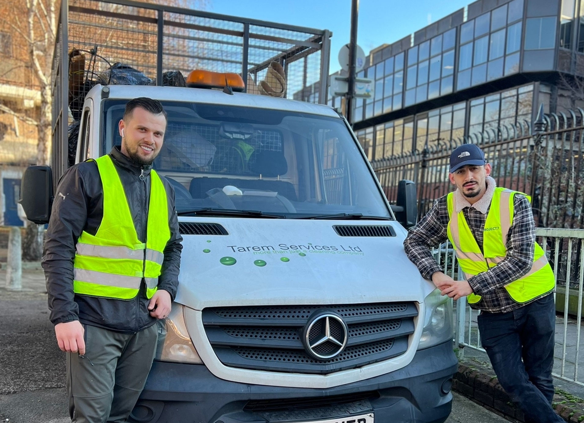 Two men in high vis jackets in front of a van