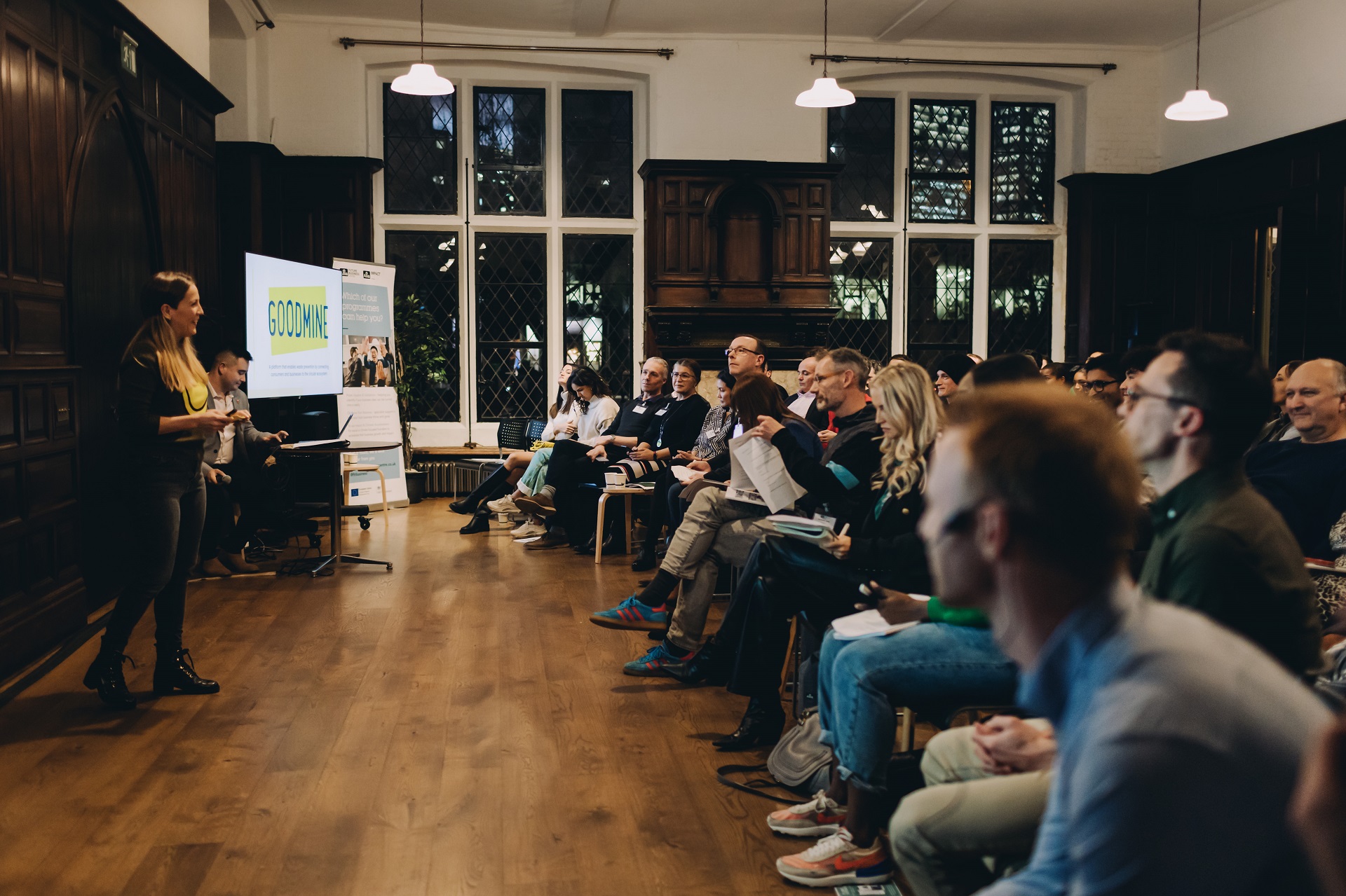 A woman delivering a presentation to a group of people for an Allia presentation