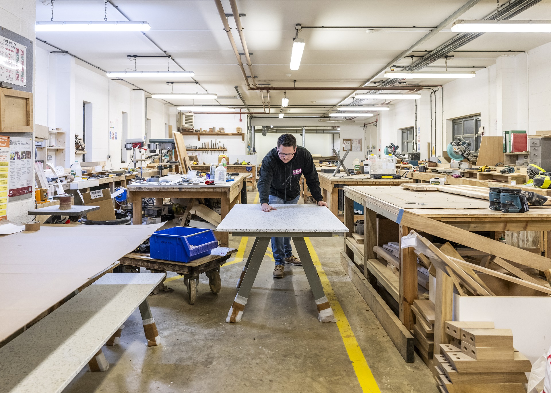 A man in a RAW branded jumper assembling a desk in a warehouse