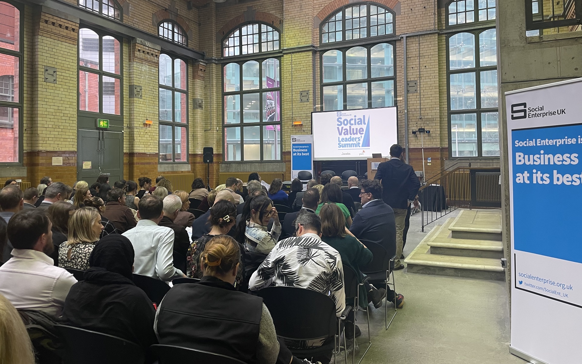 Picture of a full room at the People's History Museum for the Social Value Leaders Summit. An old Victorian building with arched windows