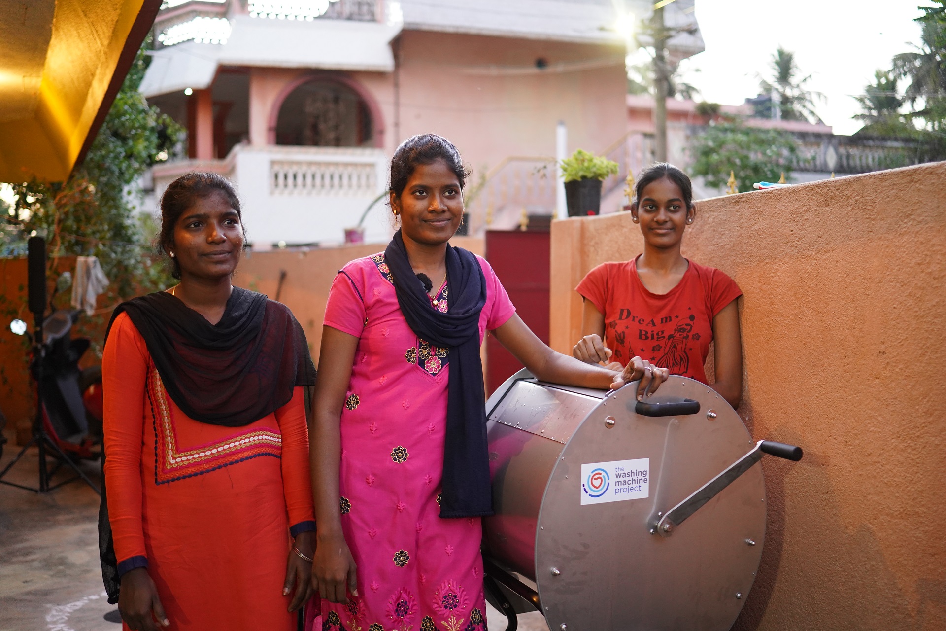3 women in India next to a Washing Machine Project manual washing machine