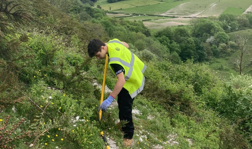 A young man in a high vis jacket on a hill side