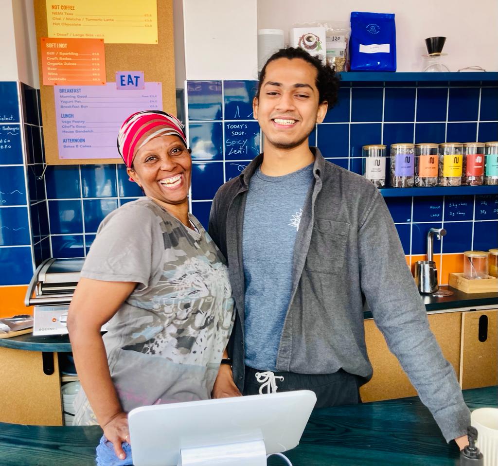 A woman and man behinid the till at Trampoline Cafe which creates job opportunities for refugees