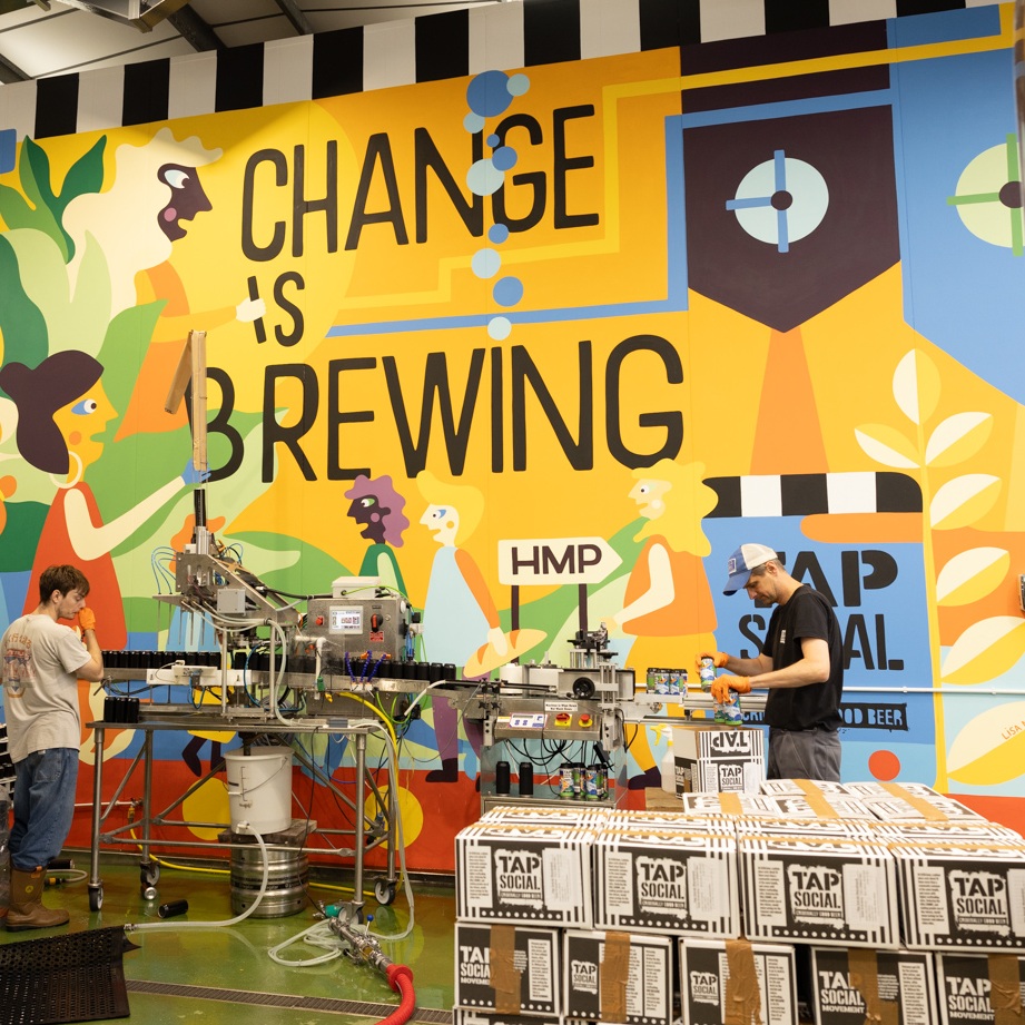 the inside of tap social brewary with the wording change is brewing in black on a yellow background