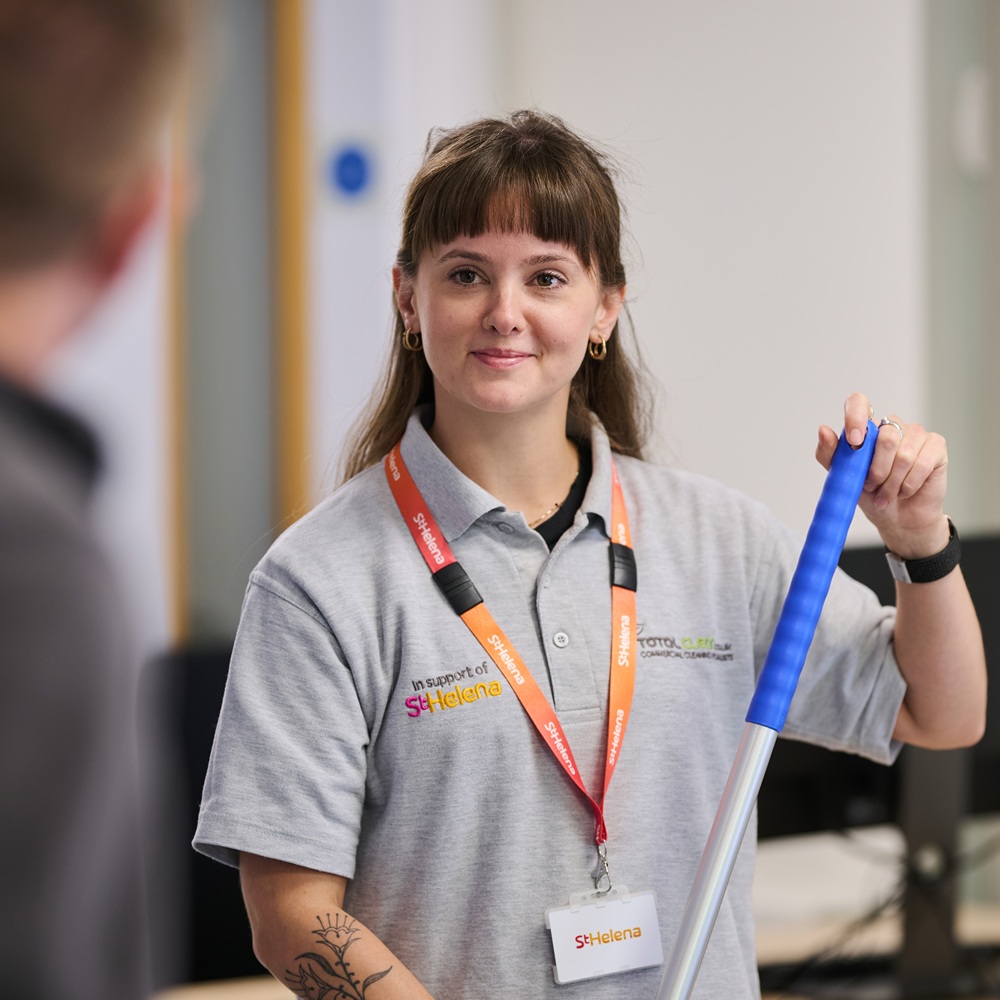 A woman holding a mop looking at the camera
