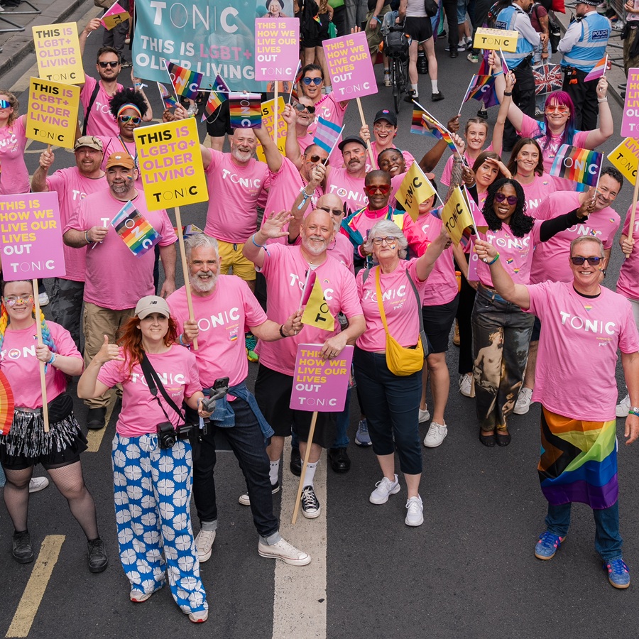 A group of people in pink t-shirts at a Pride march representing Tonic Housing